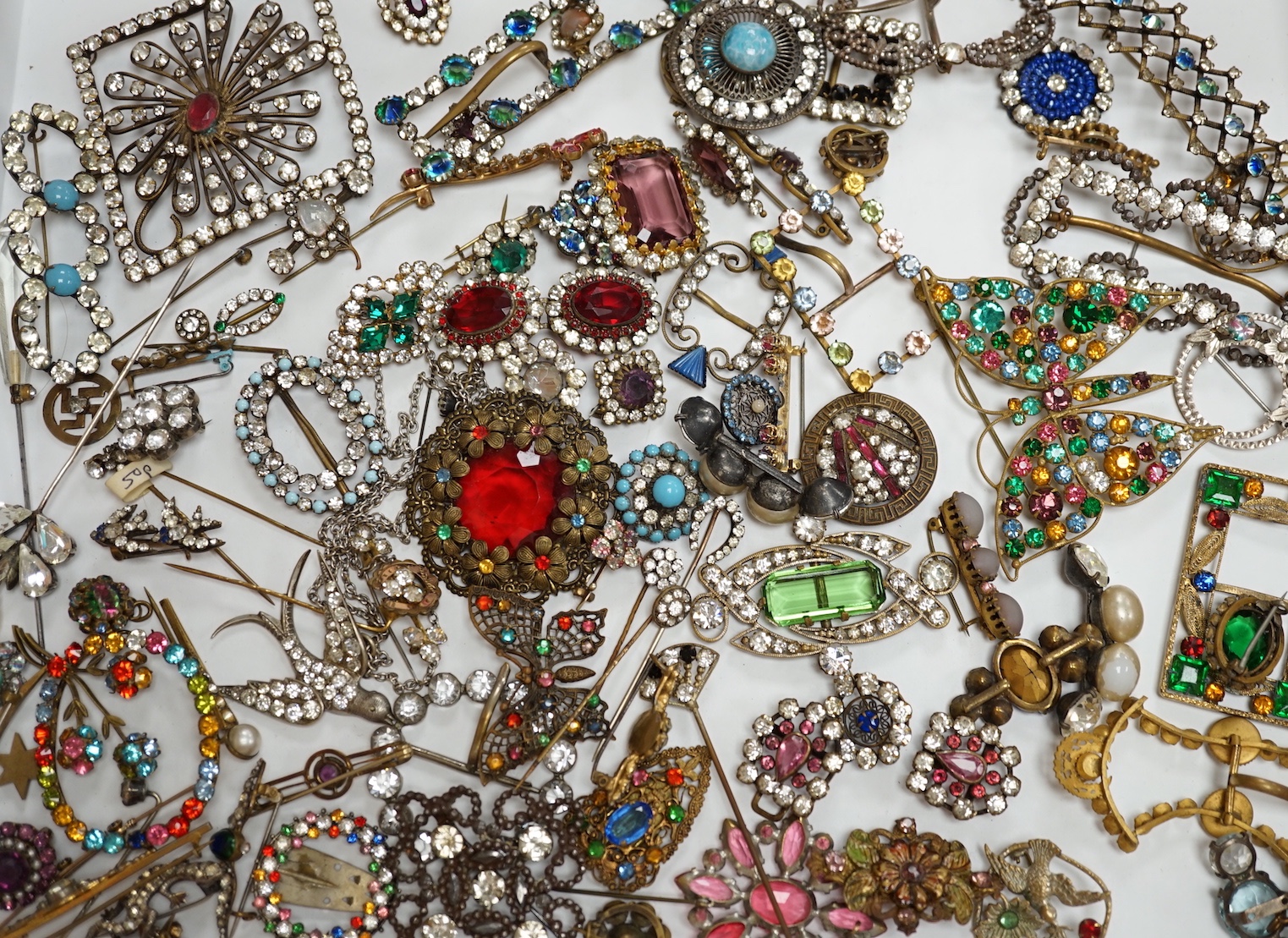 A quantity of assorted coloured and white paste jewellery, including brooches and buckles.